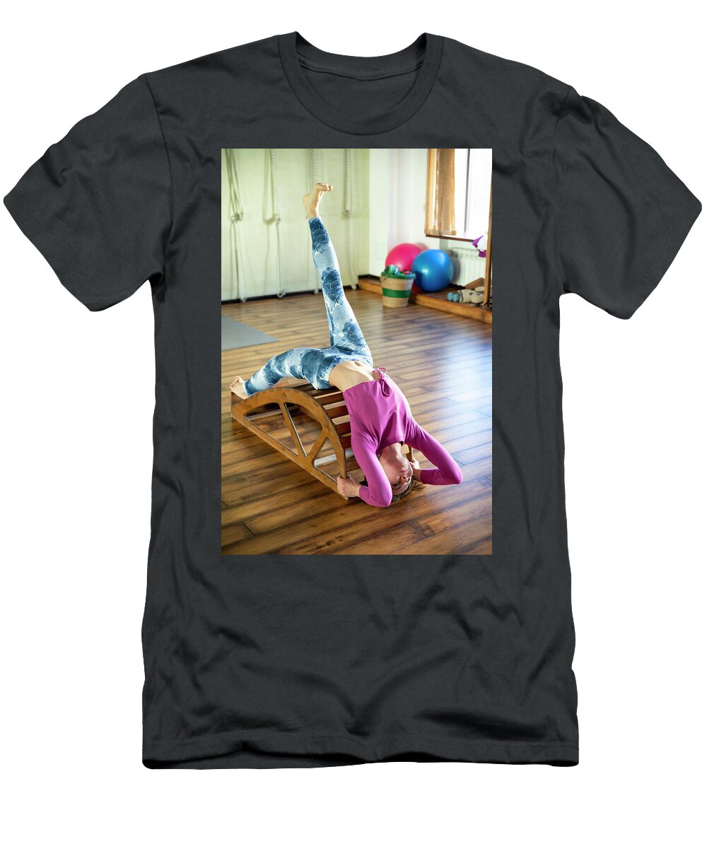 Young Woman in Yoga Pose with One Leg Up on Wooden Bench Maria Kray T-Shirt